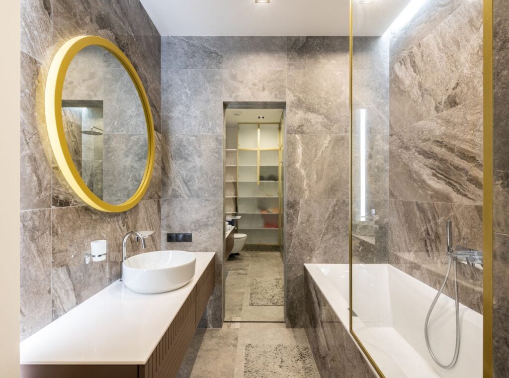 Modern bathroom with a white basin, glass shower screen and marble walls